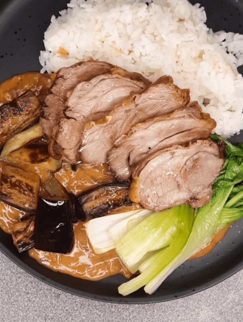 Kare-Kare Sauce topped with lamb, eggplant, and bok-choy, with rice.