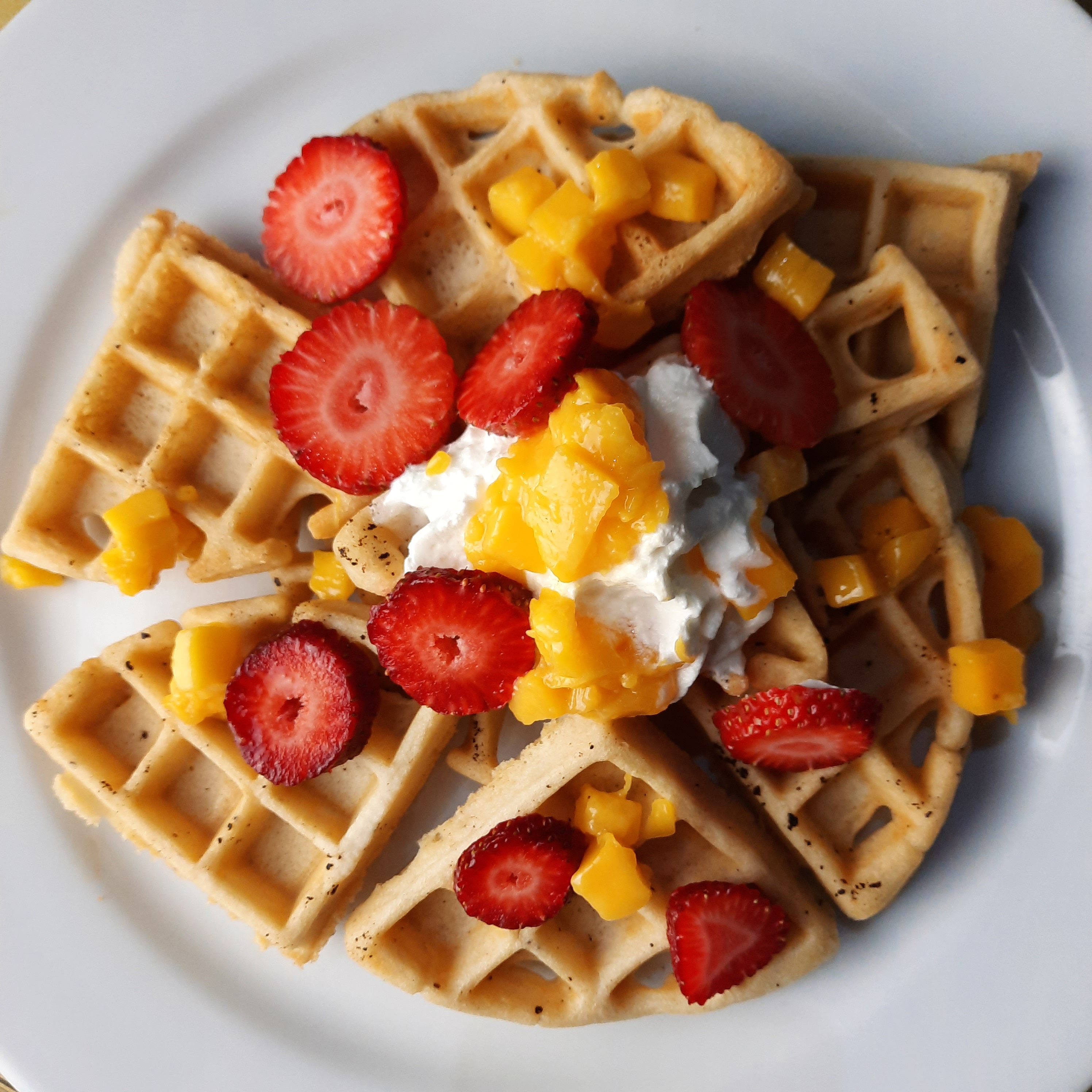 Waffle pieces topped with strawberry, mango and cream